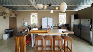 A kitchen with a central island, bar stools, a refrigerator, and a coffee maker. - Guanaglamp (Tamarindo)