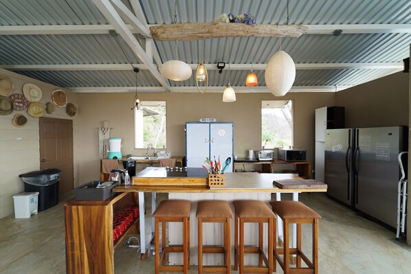 Una cocina con una isla central, taburetes de bar, un refrigerador y una cafetera.