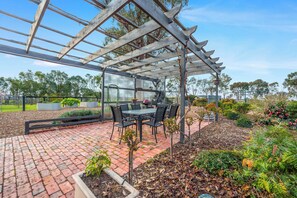 Relax in the shaded patio area, complete with a table and chairs for dining or socializing.