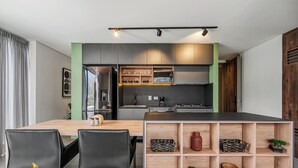 Una cocina moderna con una isla de madera, sillas negras y estantes empotrados.