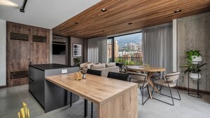 Una cocina moderna con encimera de madera, horno empotrado y comedor con mesa redonda y sillas.