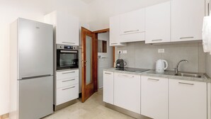 Een moderne keuken met een inbouwoven, een koelkast en een spoelbak met waterkoker.