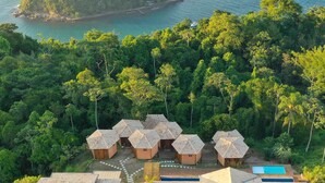 A resort with multiple thatched-roof cottages surrounded by dense forest, a small island with a beach, and a clear blue pool. - Tahaa Pousada Boutique (Ilhabela)