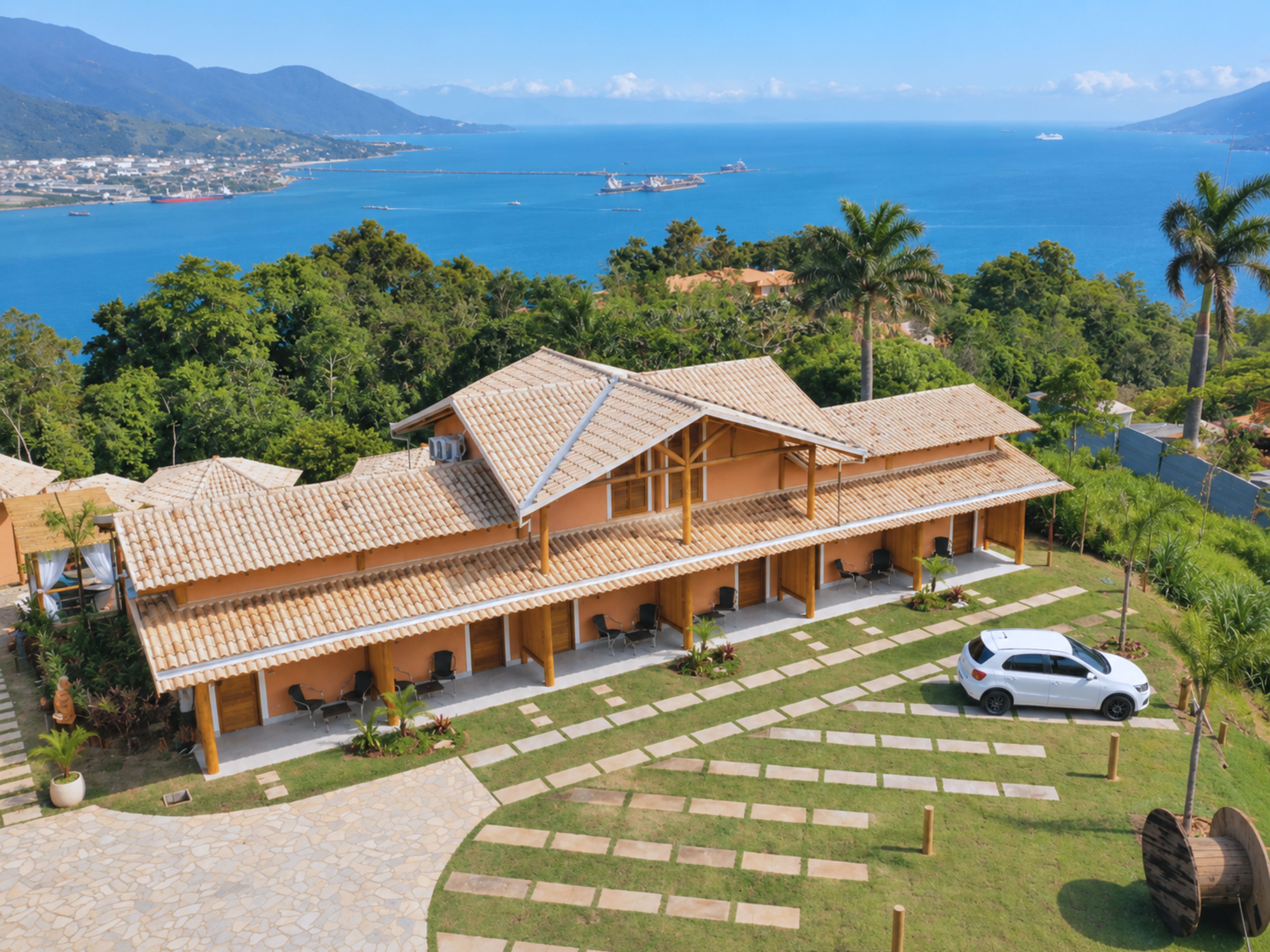 Um resort com um prédio grande, um caminho de acesso pavimentado e vista para o oceano.