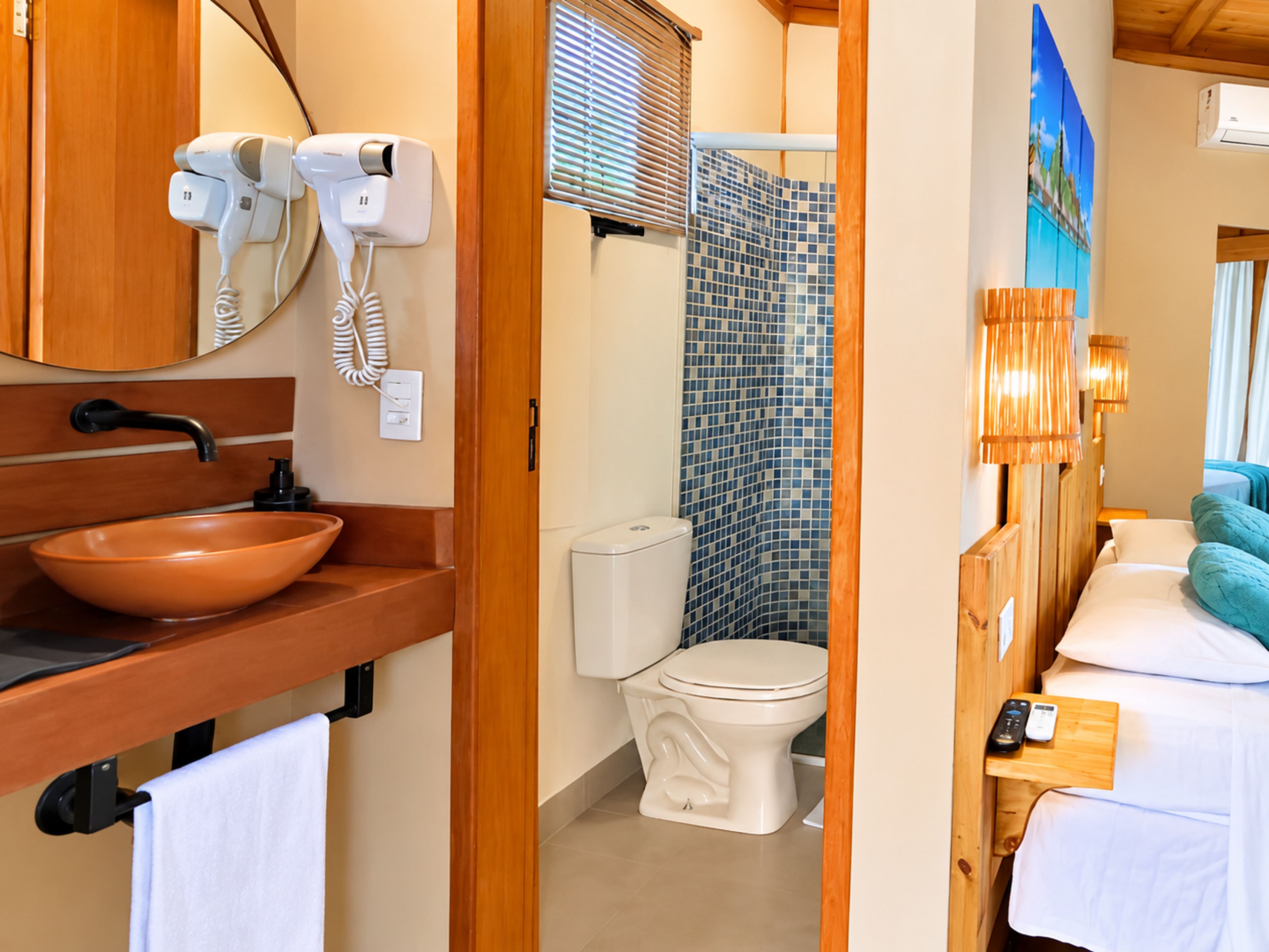 Un baño con tocador de madera, lavamanos, inodoro y zona de ducha.