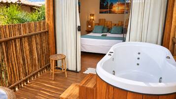 A wooden deck with a hot tub, a bed with pillows, and a painting on the wall.