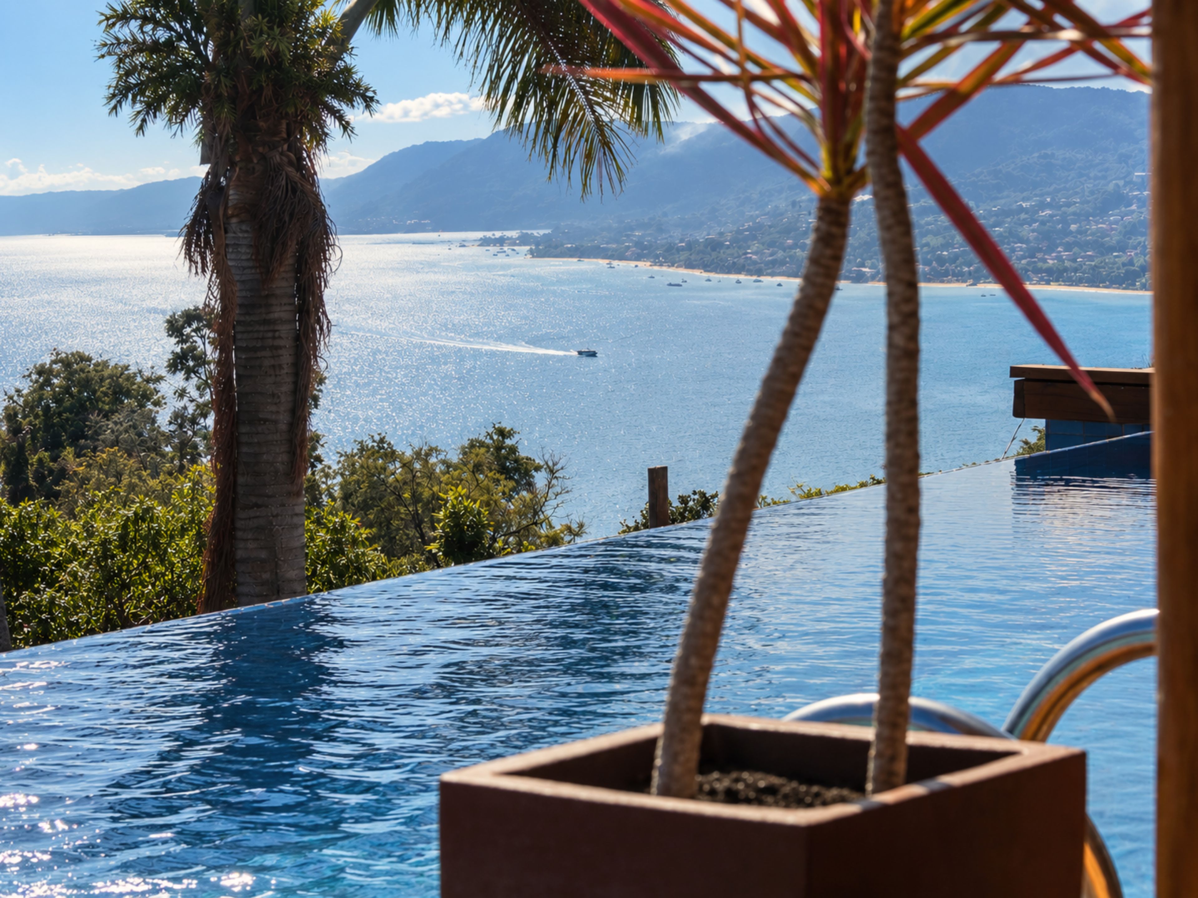 A pool with a view of the sea and mountains.
