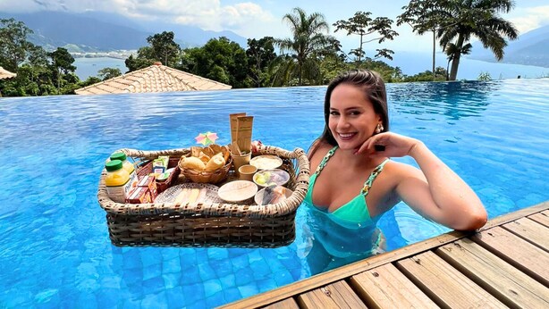A woman in a pool with a floating basket containing food and drinks. - Tahaa Pousada Boutique (Ilhabela)