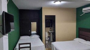 Une chambre d’hôtel avec deux lits, une télévision, une petite table et une salle de bain visible à travers une porte ouverte.