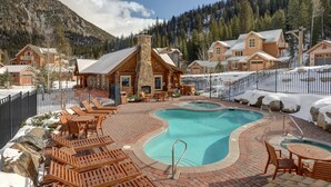 A resort with a swimming pool, wooden deck seating, and cabins in a mountainous area. - Gorgeous Ski Escape with Fireplace and Balcony (Keystone)