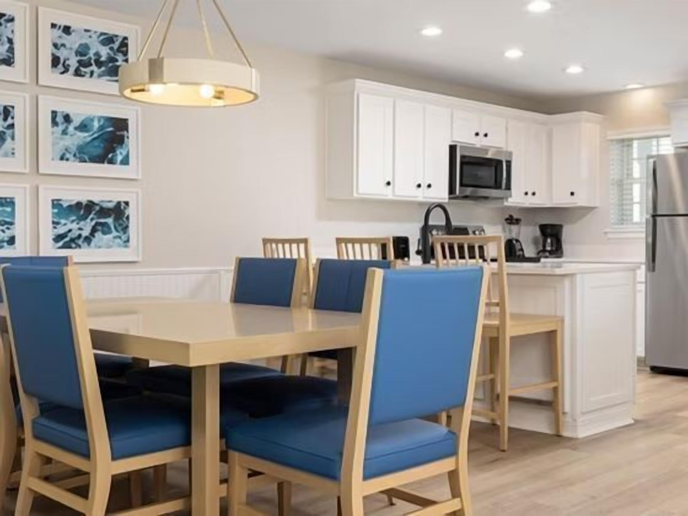 A modern kitchen with white cabinets, a microwave, and a stainless steel refrigerator.