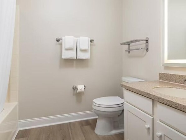 A bathroom with a toilet, two towels on a rack, a sink, and a mirror.