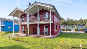 Une maison à deux étages avec un balcon, une antenne parabolique et un petit espace porche.