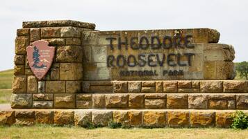 Un letrero de piedra con la leyenda "Theodore Roosevelt National Park" y el emblema del Servicio de Parques Nacionales.