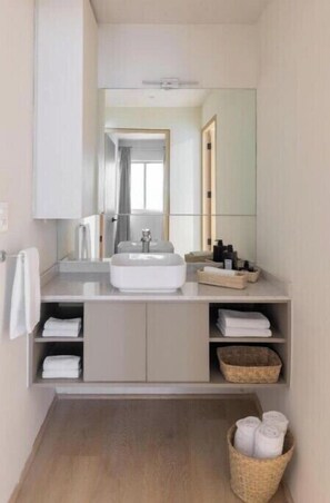 Bathroom features a large mirror, sink, and two cabinets.