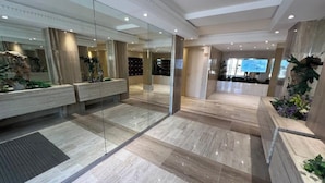 A spacious lobby with a marble floor, a glass partition, and a reception area with a television.