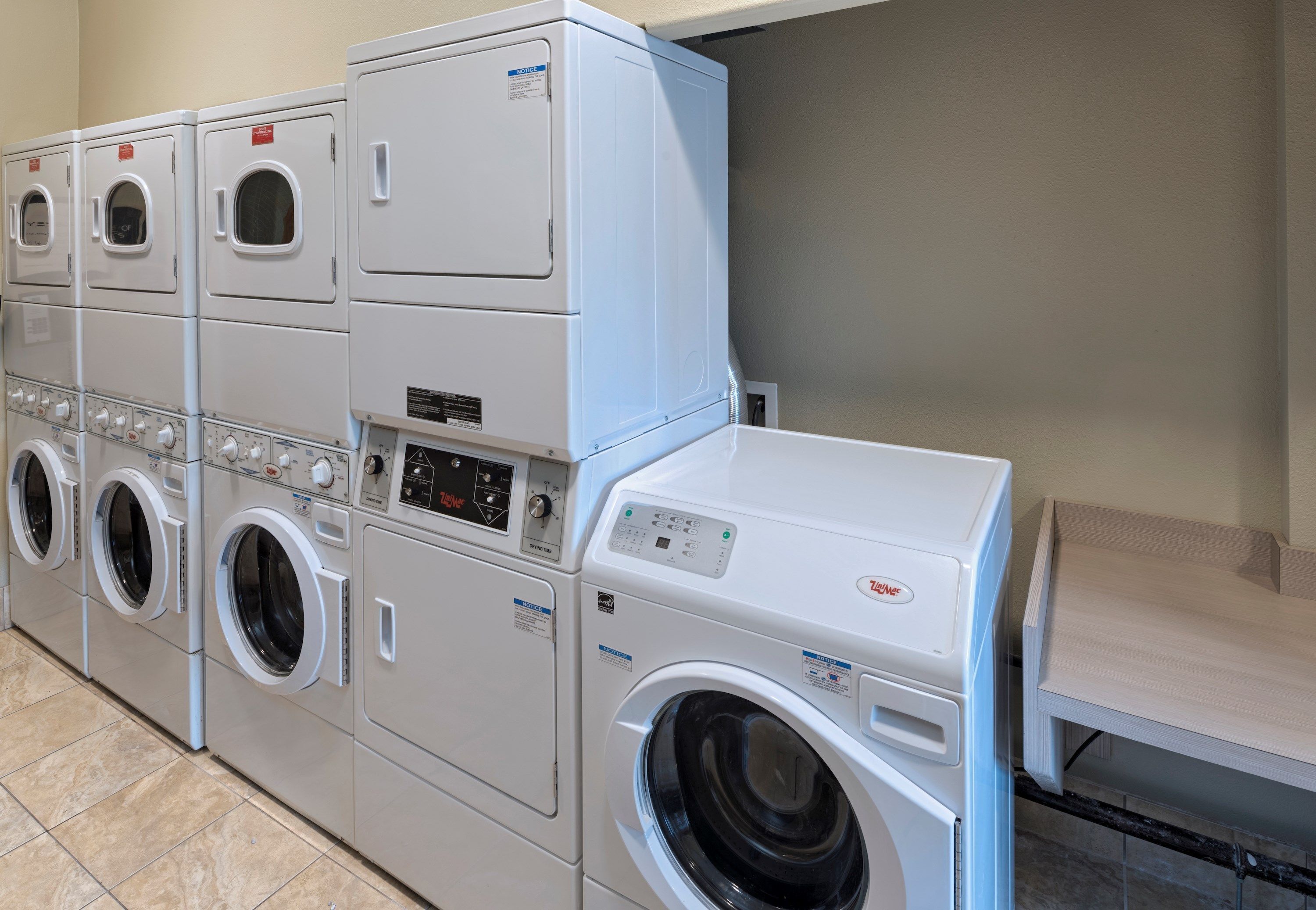 Een rij gestapelde wasmachines in een commerciële omgeving.