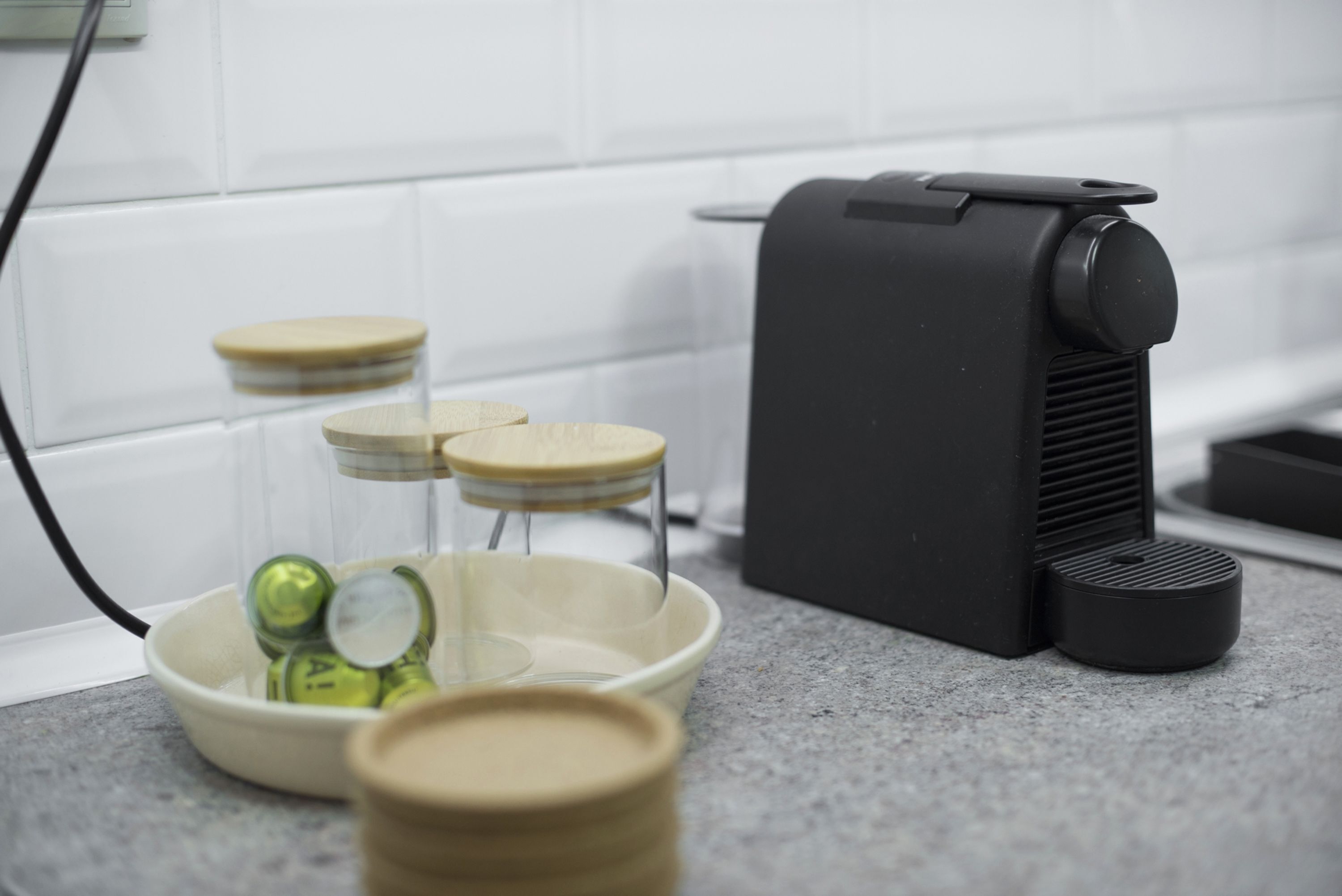 Eine Küche mit einer Kaffeemaschine, einer Schüssel mit Deckeln und einem Behälter mit grünen Deckeln.