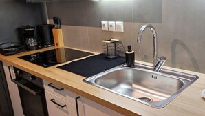 A modern kitchen with a stainless steel sink, black countertop, and a black coffee maker. - Studio Stratos With 1 Bathrooms (Athens)