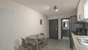 A modern kitchen with a dining area, featuring a round table with chairs, a built-in oven, and a stainless steel sink. - Studio Stratos With 1 Bathrooms (Athens)