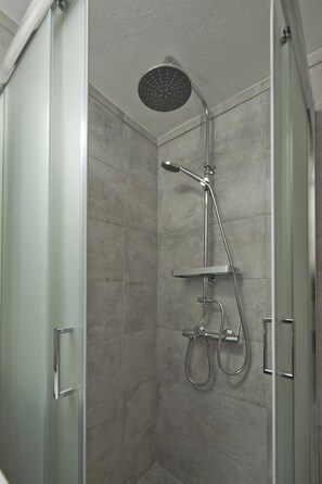 A glass-enclosed shower stall with a handheld showerhead and a wall-mounted faucet. - Studio Stratos With 1 Bathrooms (Athens)