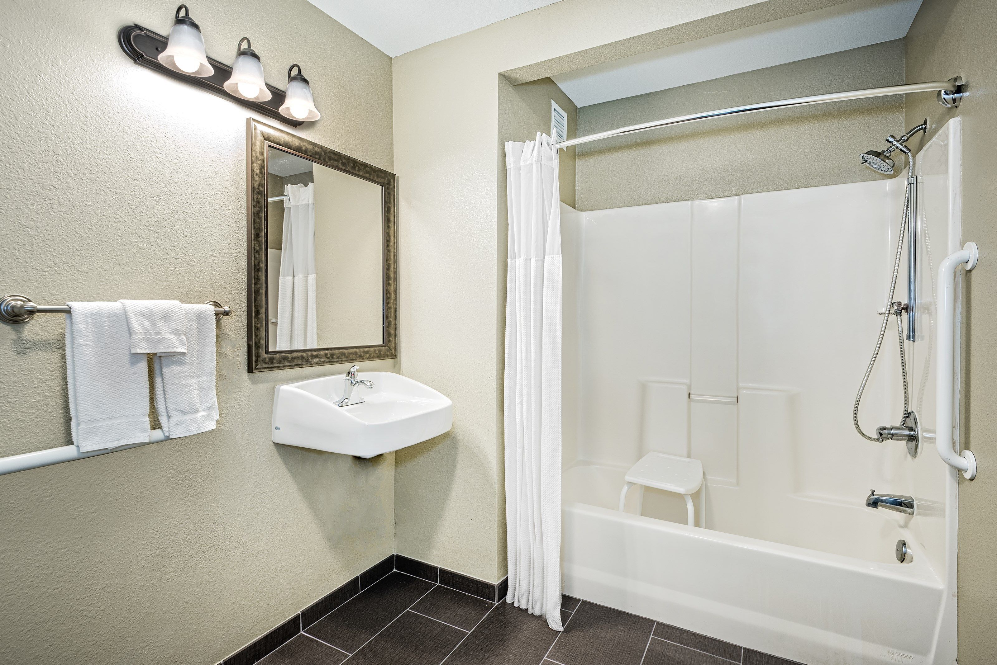 A bathroom with a sink, mirror, and shower.