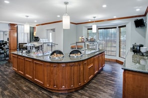 Una cocina con isla central, armarios de madera y encimera de granito.