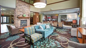 A spacious lobby with a fireplace, seating area, and a view of the kitchen.