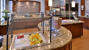 A buffet area with a variety of food options, including fruits and cereals, and a Coca-Cola refrigerator.