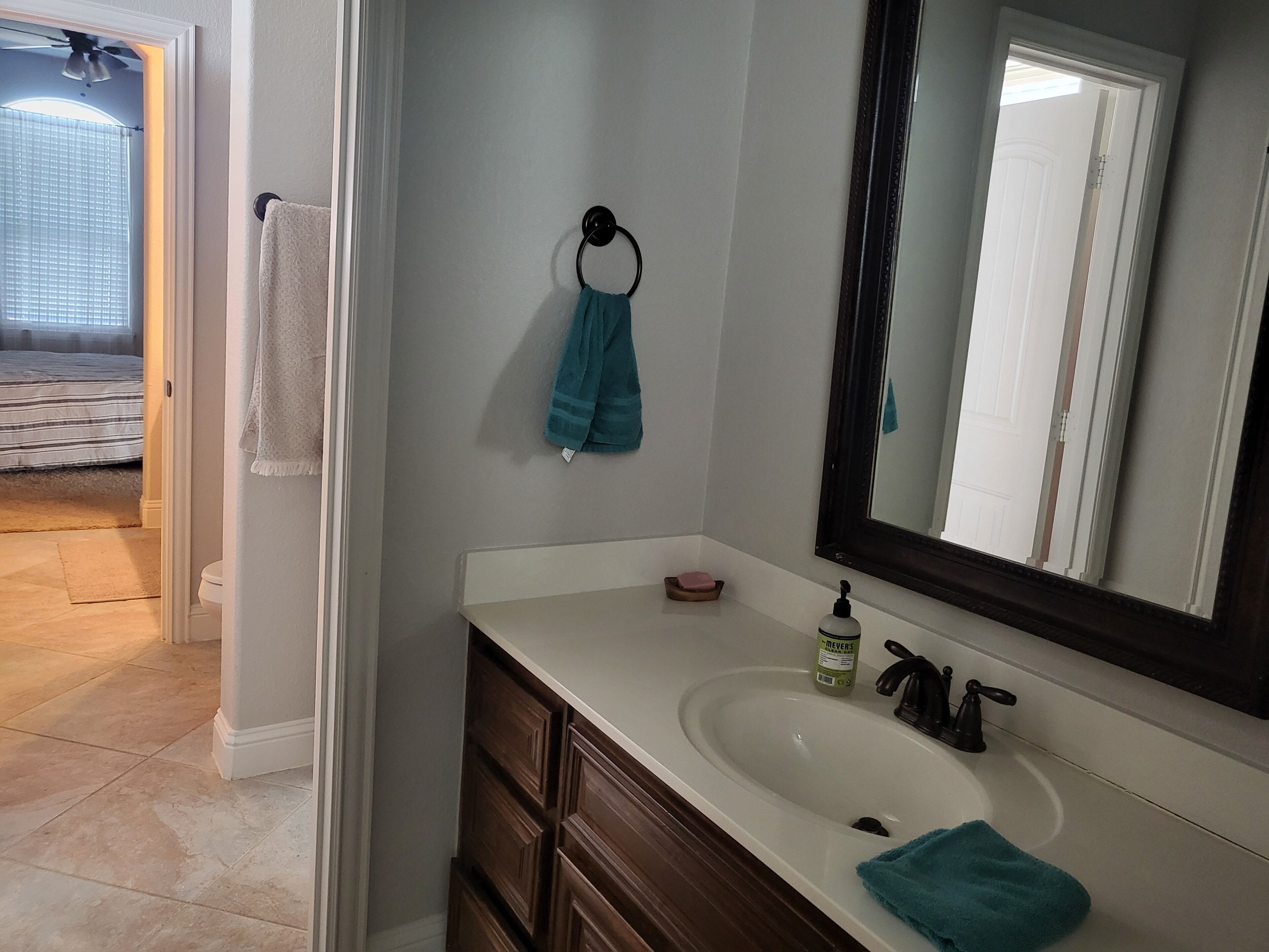 A bathroom with a white sink, dark wooden cabinets, a mirror, and a towel rack with a blue towel.