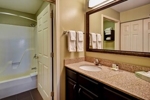 Une salle de bain avec une baignoire, un lavabo, un miroir et un porte-serviettes.