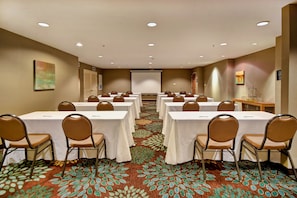 A conference room with multiple tables and chairs, a projector screen, and a carpeted floor. - Free Breakfast. Pool & Hot Tub. Near East Towne Mall! (Madison)