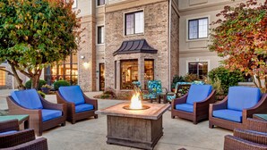 An outdoor seating area with wicker furniture and a central fire feature. - Free Breakfast. Pool & Hot Tub. Near East Towne Mall! (Madison)