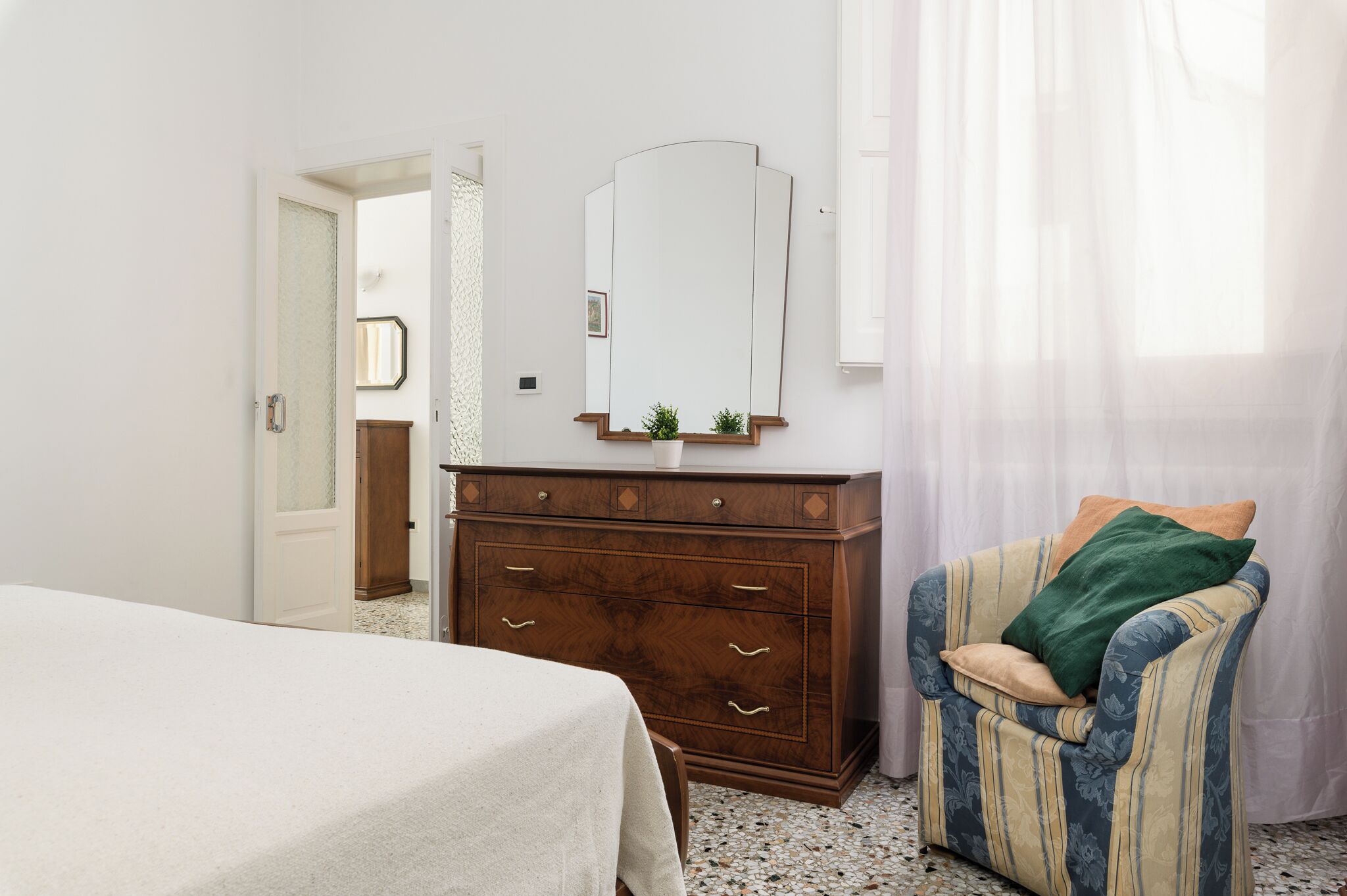 Een slaapkamer met een bed, een kaptafel, een stoel en een spiegel.