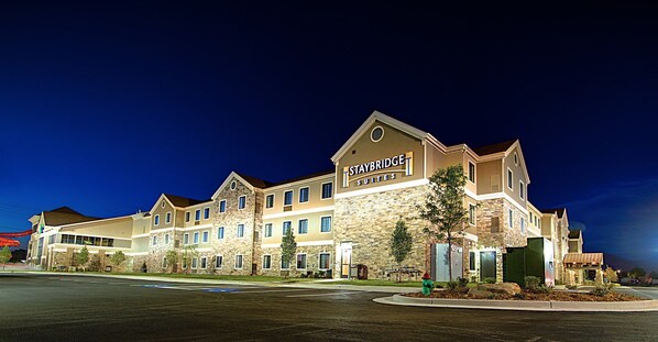 A Staybridge Suites hotel with a stone facade, multiple windows, and a well-lit entrance.