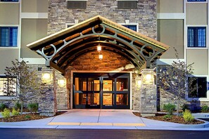 A building entrance with a stone facade, a wooden arch, and a glass door.
