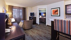 Una habitación de hotel con escritorio, silla, televisor y cama.