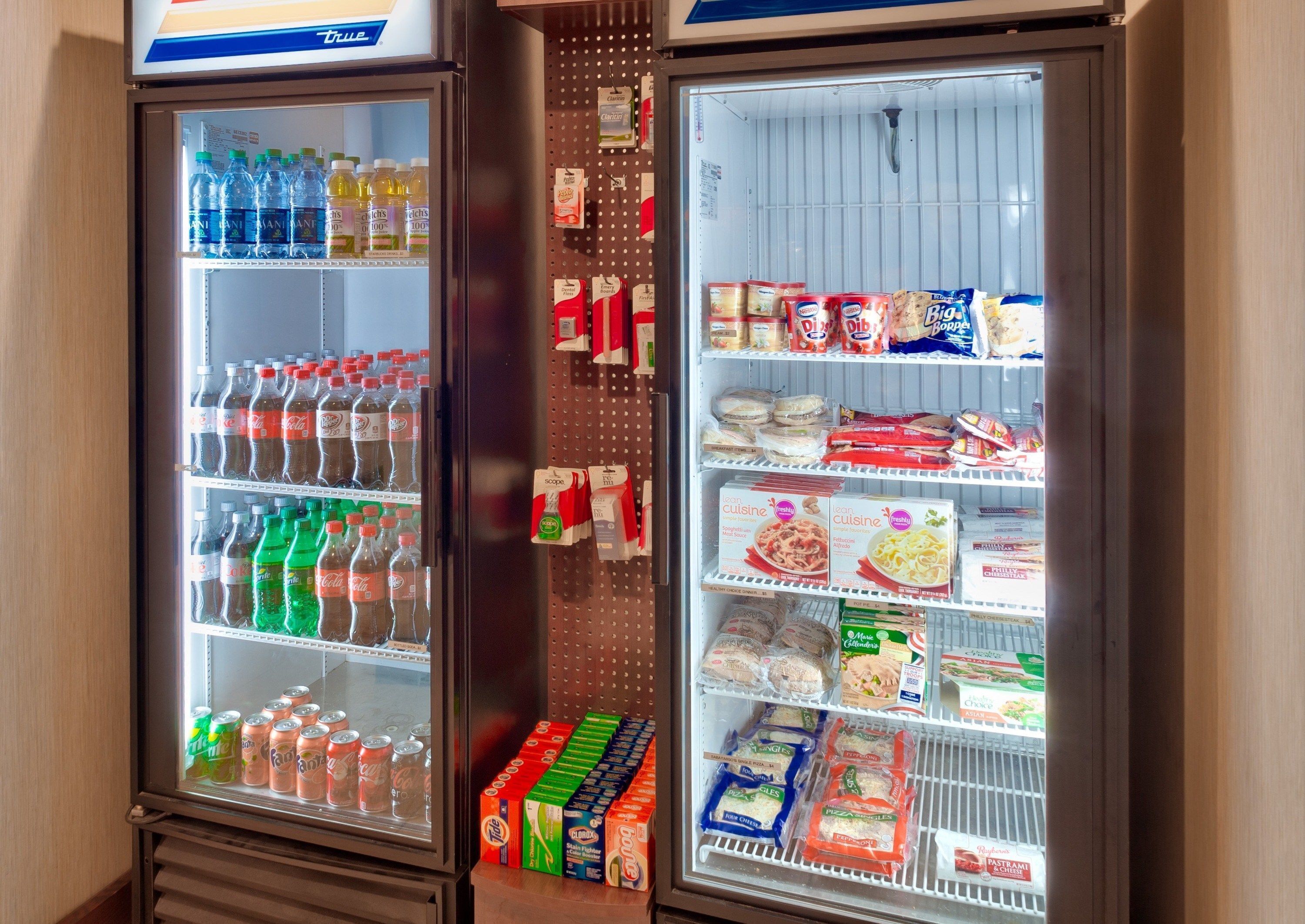 Deux distributeurs automatiques de boissons, remplis de diverses boissons, et un présentoir réfrigéré contenant des aliments emballés.