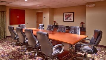 A conference room with a large table, six chairs, a red cabinet, and a framed picture on the wall.