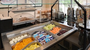 Een buffet met diverse gerechten, waaronder fruit, gebak en drankjes.