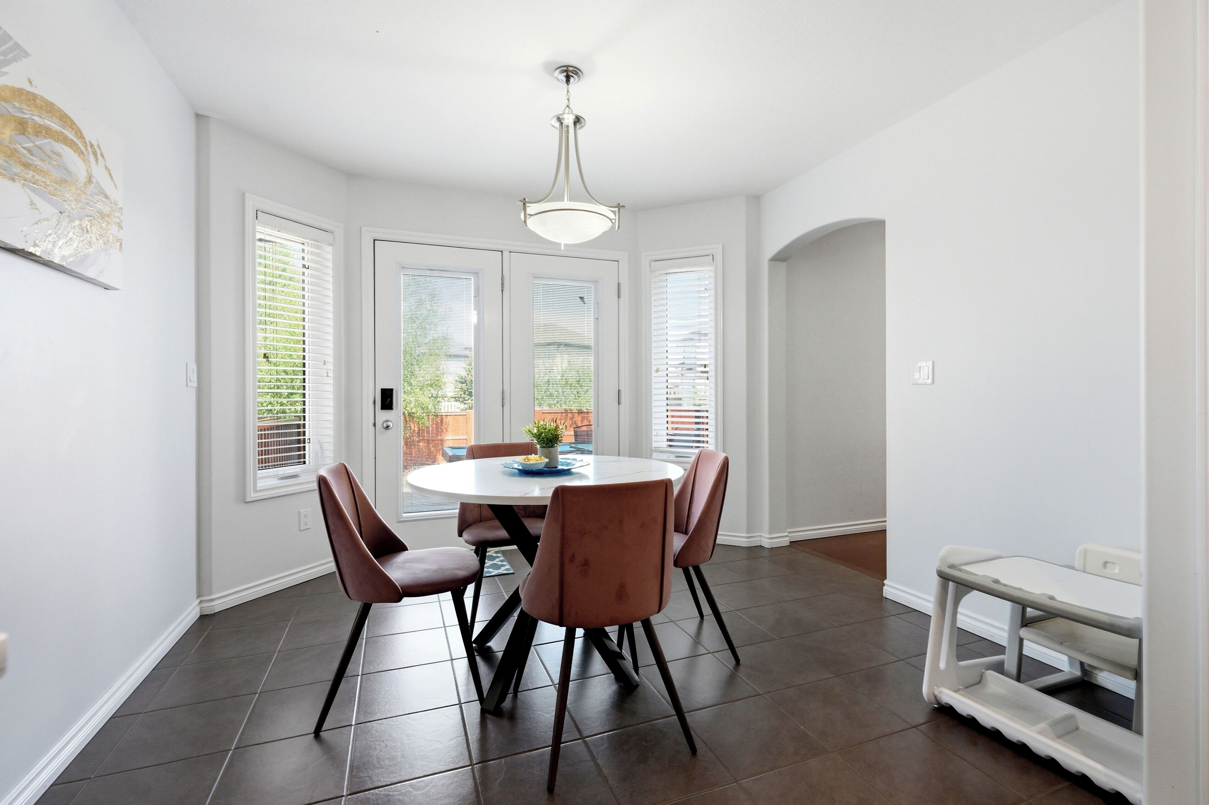Un coin repas avec une table ronde, six chaises et un luminaire suspendu.