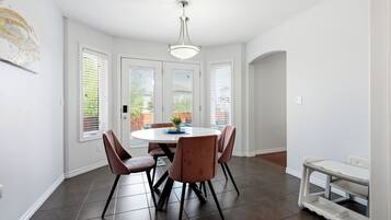 Un coin repas avec une table ronde, six chaises et un luminaire suspendu.