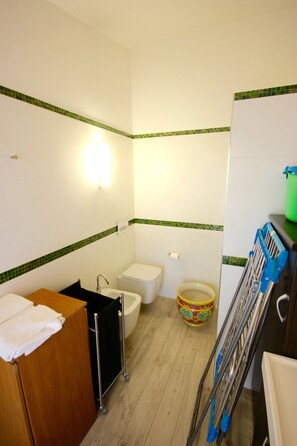 A compact bathroom with a wooden vanity, a toilet, a sink, and a shower area.