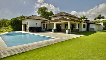 A two-story house with a swimming pool, a covered patio, and a well-maintained lawn.