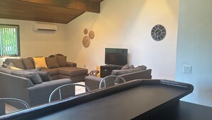 A modern living room with a built-in bench, a flat-screen TV, and decorative wall art. - The Sequim Tree House is a spacious one bedroom with a bonus room for more guest (Sequim)