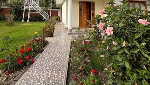 A two-story house with a balcony, a staircase, and a garden with flowers. - Casa Oxapampa (Oxapampa)