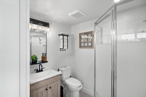 Un baño moderno con lavamanos, espejo y retrete blancos.