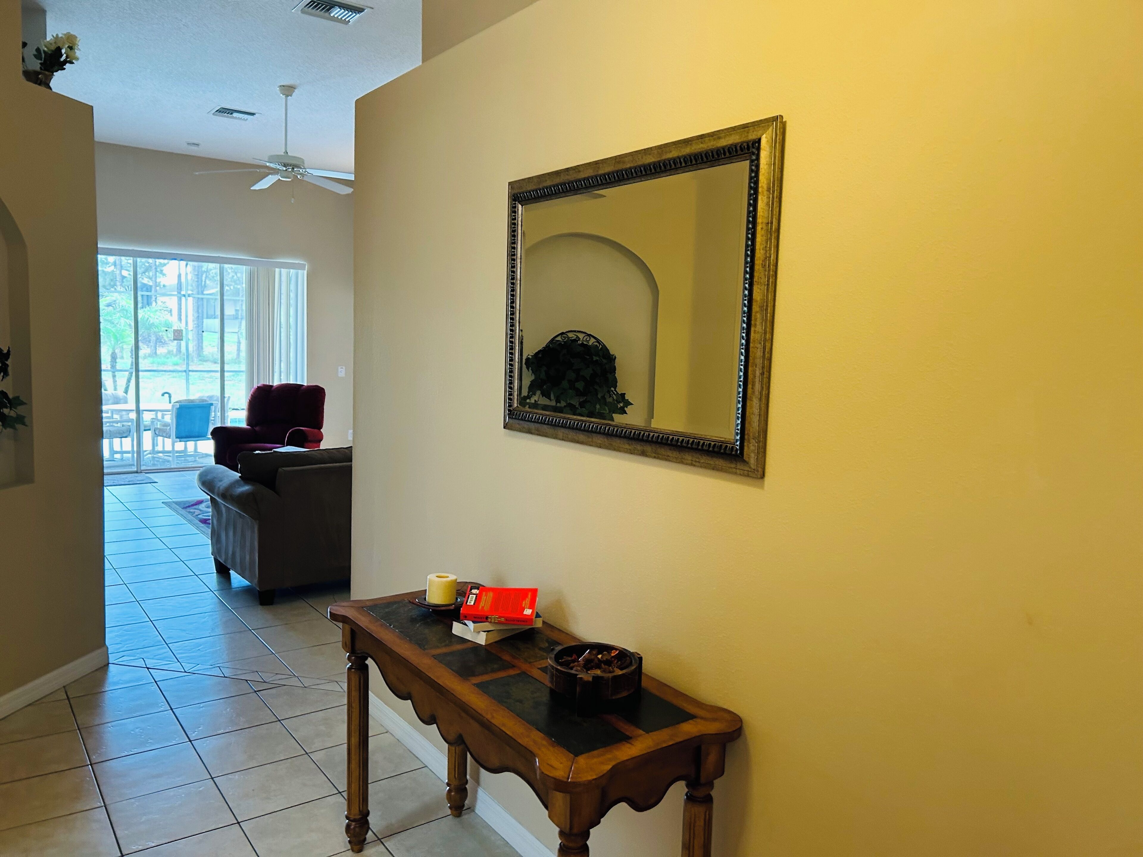 A hallway with a wooden console table, a mirror, and a ceiling fan.