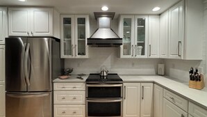 A modern kitchen with stainless steel appliances, white cabinetry, and a tiled backsplash.