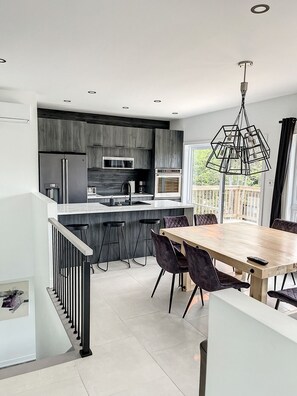 A modern kitchen with dark wood cabinets, a stainless steel refrigerator, and a built-in microwave.